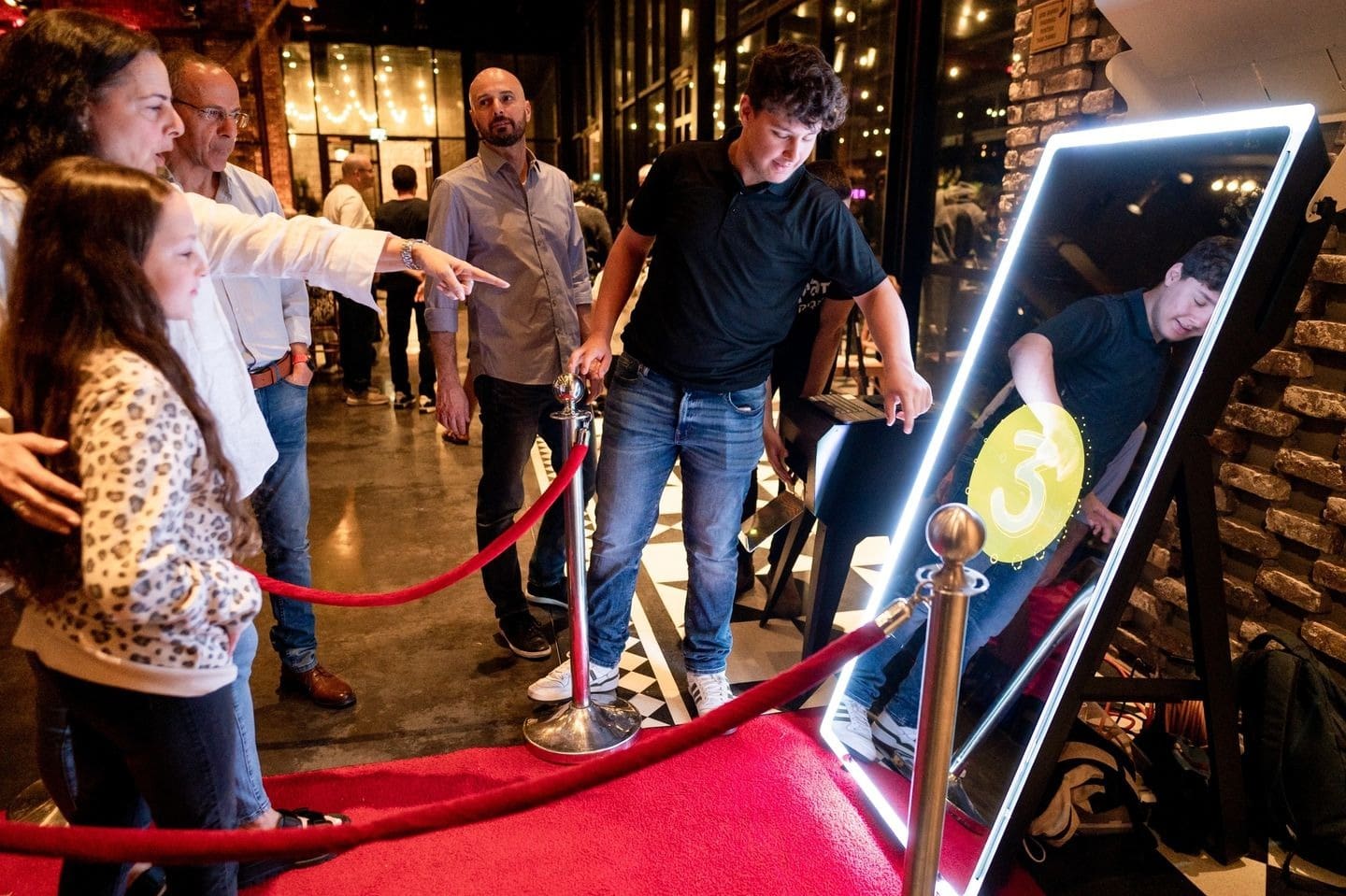 A group of people standing around a red carpet.