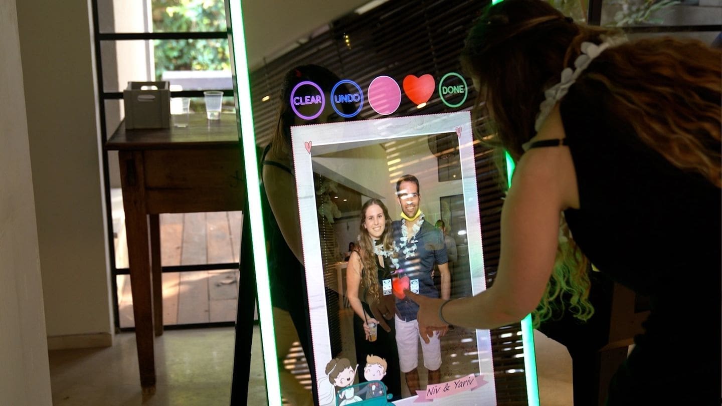 A woman is holding a selfie frame with a picture of two people.